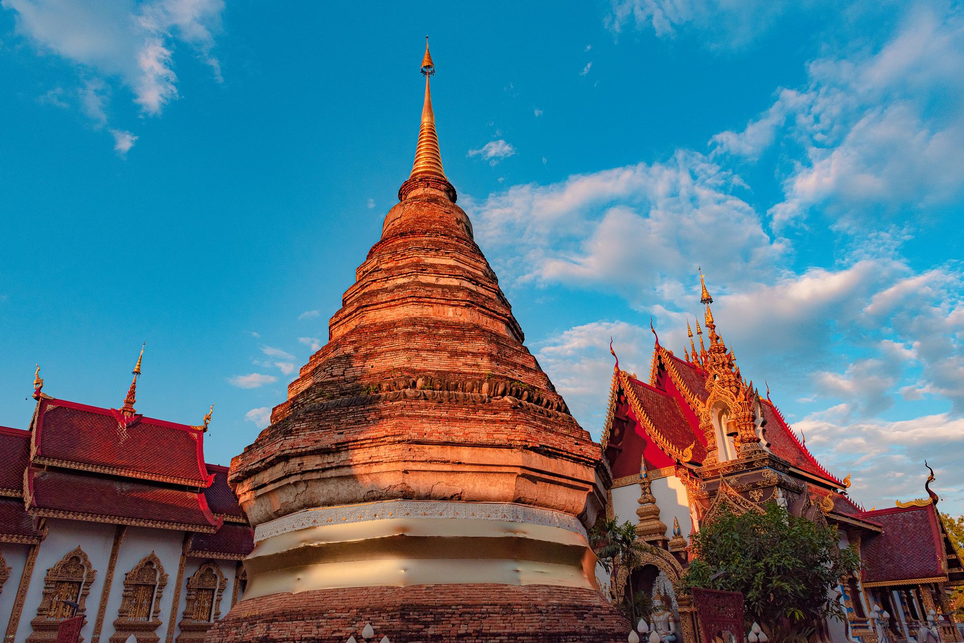 A gilded Thai temple roof against a bright blue sky in Chiang Mai, Thailand