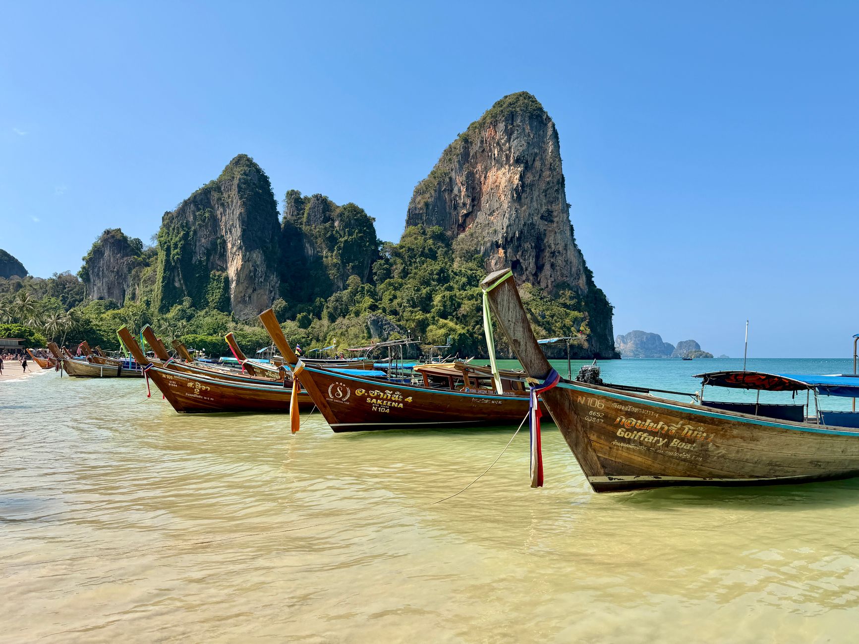 Longtail boats on the sand at Railay Beach, Krabi, with limestone cliffs behind