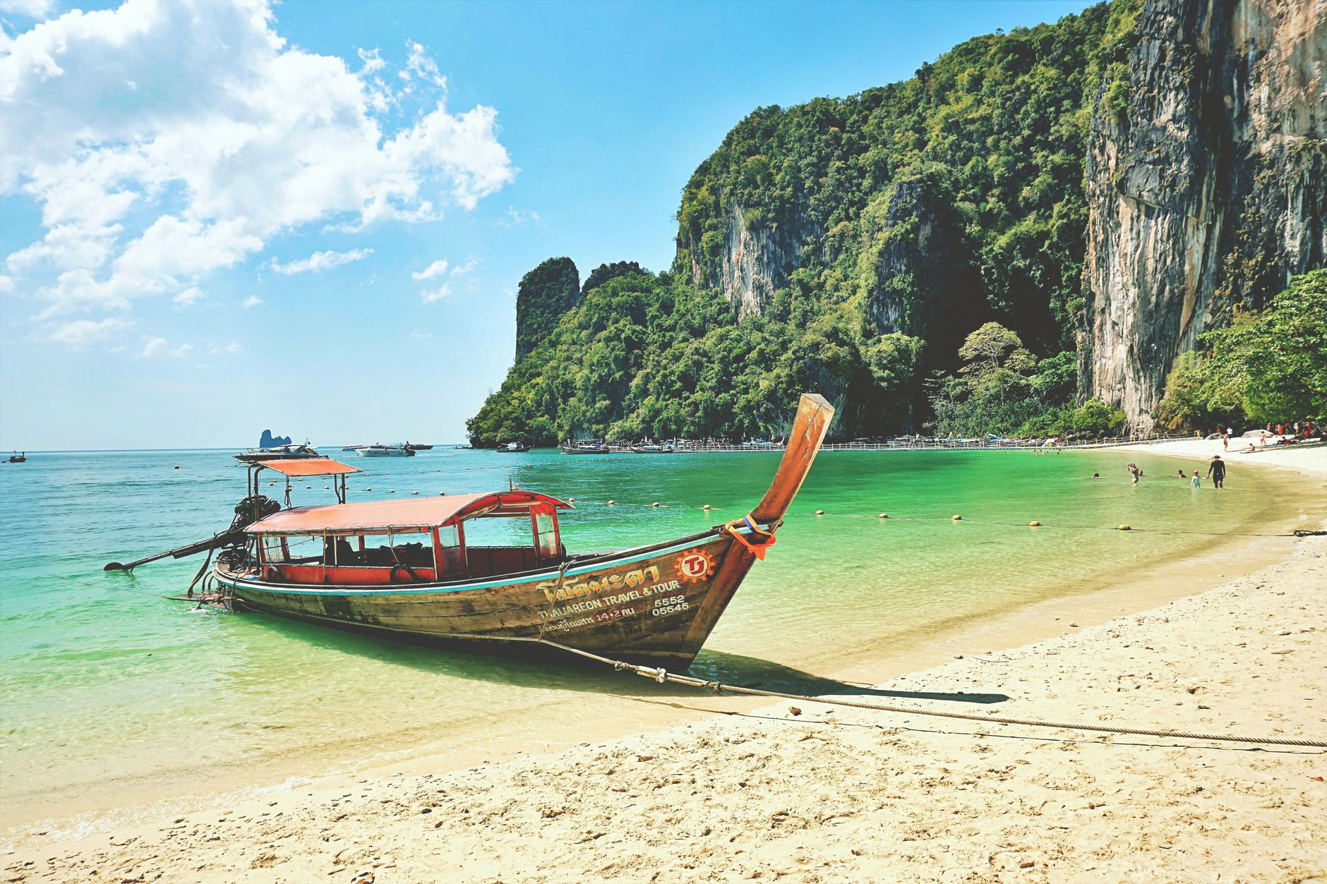 Longtail boat on a Krabi beach with limestone cliffs rising behind it