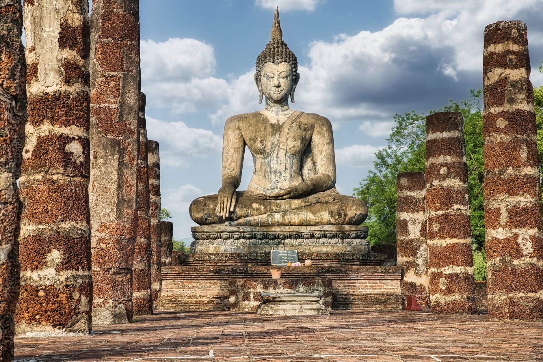 Seated Buddha statue among the brick ruins of Sukhothai Historical Park in early light