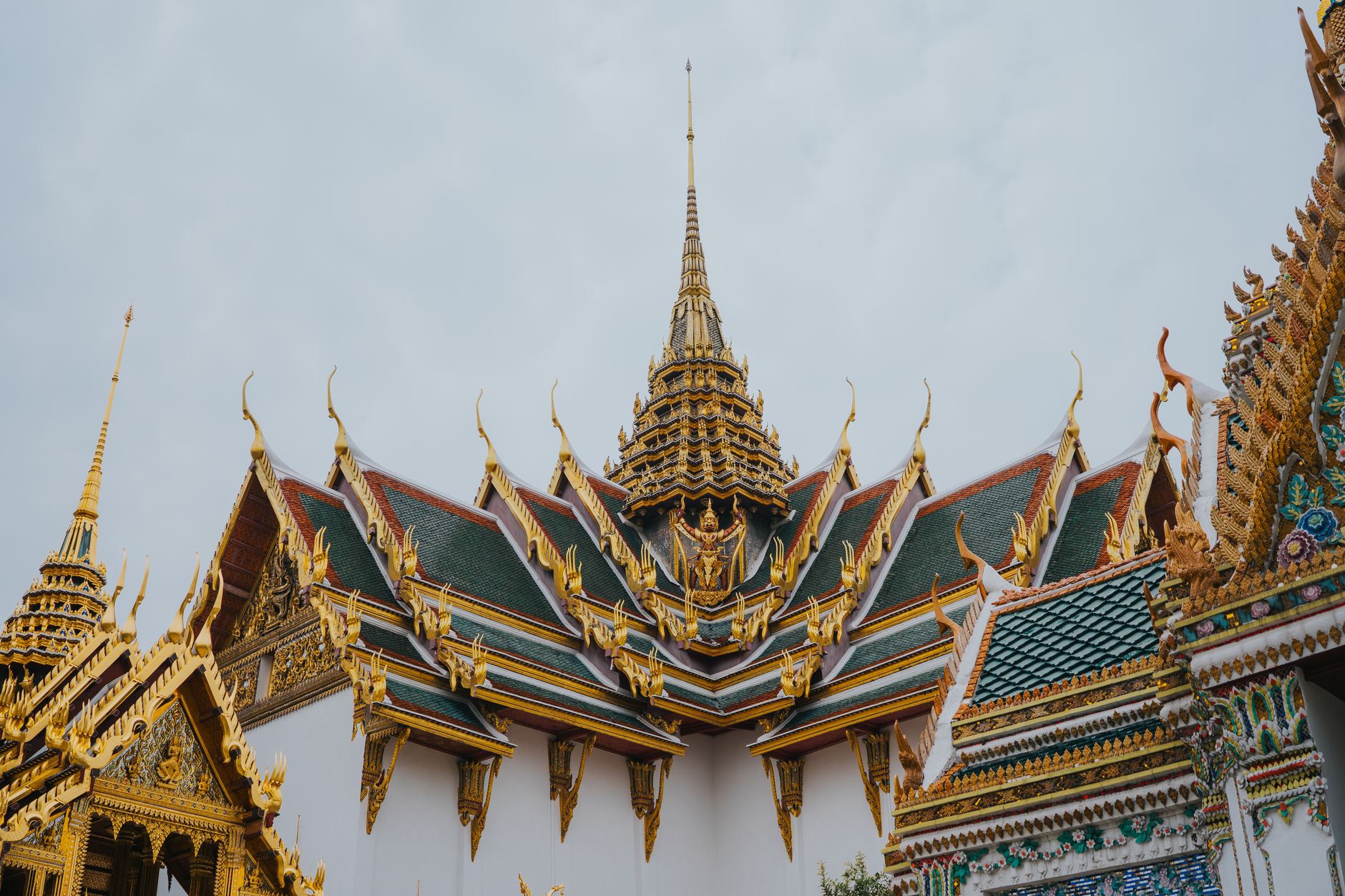 Layered green-and-gold tiled roofs with chofa finials at Wat Phra Kaew in Bangkok